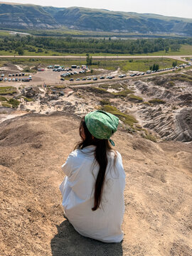 Woman sitting on badlands hoodoo overlooking Drumheller valley Alberta