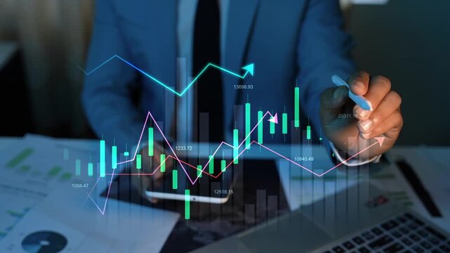 Holographic growing stock market chart animation, Businessman in a blue suit analyzes glowing hologram stock charts on a digital screen above a desk with financial papers and a laptop