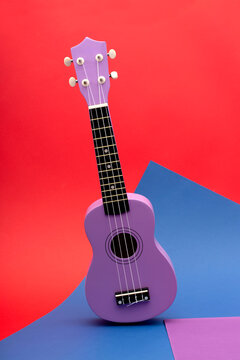 Four string ukulele guitar on red and blue background