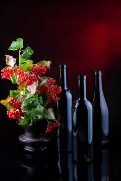 Still life with glass bottles and red viburnum