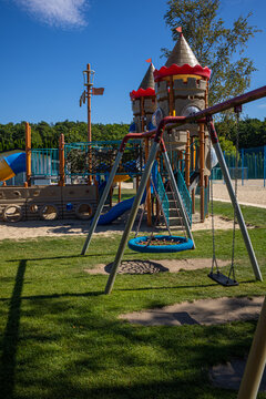 Children's Slides and Swings in Outdoor Recreation Area. Outdoor children's recreation area at a holiday resort with colorful slides, swings and climbing structures. The playground is surrounded by gr