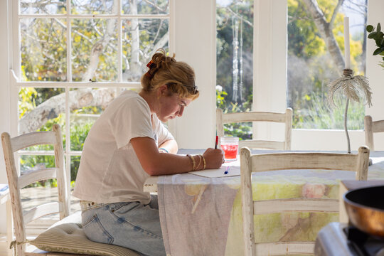 young woman drawing at table in light filled room