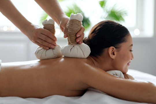 Beautiful woman unwinding during premium herbal spa therapy session, enjoying gentle heat, aromatic herbs and expert massage techniques for total relaxation