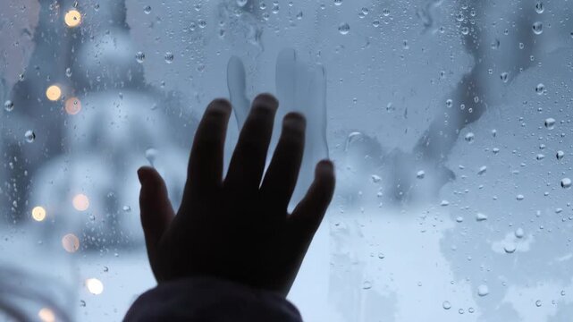 Raindrops on window with blurred silhouette, moody rainy mood