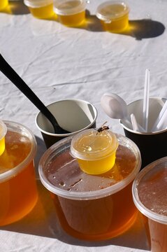 Fresh natural honey in plastic containers on a vintage linen tablecloth with a bee. Honey Spas Slavic holiday market, amber sweet treat, traditional fair, sunny summer day, rustic aesthetic