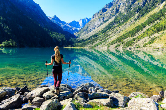 Woman hiker admiring the crystal clear waters of lac de gaube in the pyrenees
