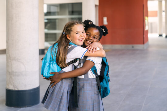 Happy diverse schoolgirls hugging, symbolizing friendship, diversity, and education starting a new school year