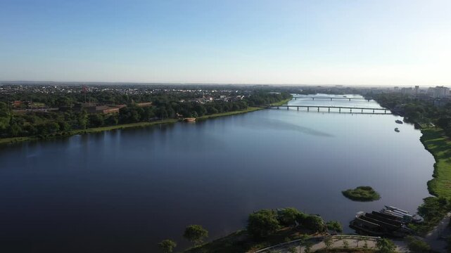 Aerial drone view of the Perfume River in Hue, Vietnam, featuring the iconic Truong Tien Bridge and Phu Xuan Bridge, with scenic riverbanks and the historic cityscape.