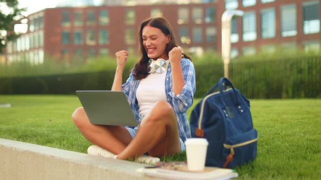 Excited lady student reacting to great news on her laptop, raising clenched fists receiving acceptance letter or excellent exam results, 4K