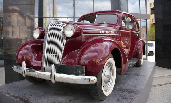 Ufa, republic of Bashkortostan, Russia- 04.26.2026. Burgundy vintage Oldsmobile car with whitewall tires. Urban outdoor photography with reflections