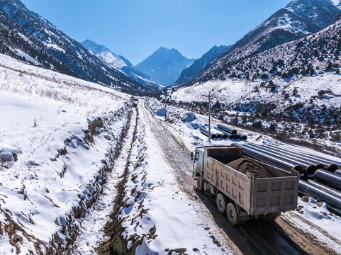 Dump Truck Hauling Gravel on Snowy Mountain Road in Kyrgyzstan