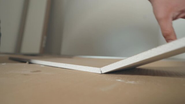 Hands sorting and separating white flat-pack furniture panels from cardboard packaging