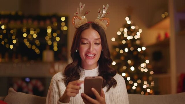 Surprised woman looking at smartphone during Christmas and celebrating with clenched fists