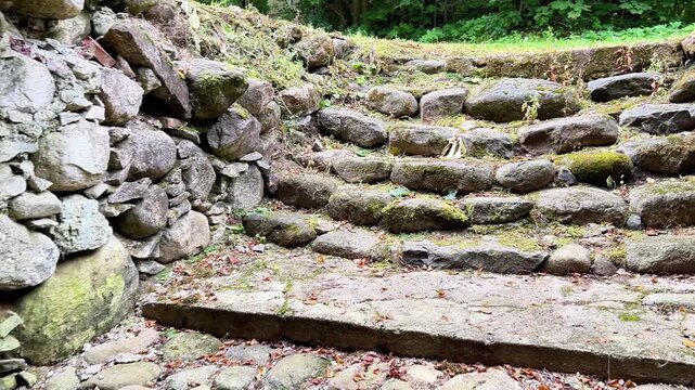 Ground-level view looking outward through an ancient stone doorway to cobble steps and a rock wall. Ideal for historical documentaries, travel, and architectural media.