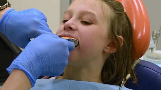 Orthodontist takes dental impression of girl's teeth with alginate tray for custom removable orthodontic expansion appliance.
