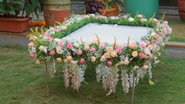 Square wedding canopy base decorated with fresh flowers on outdoor lawn in India