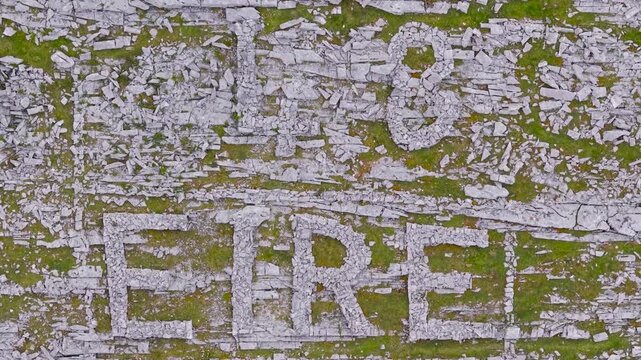Aerial view of Eire sign formed by white limestone rocks on green grass landscape in Ireland.