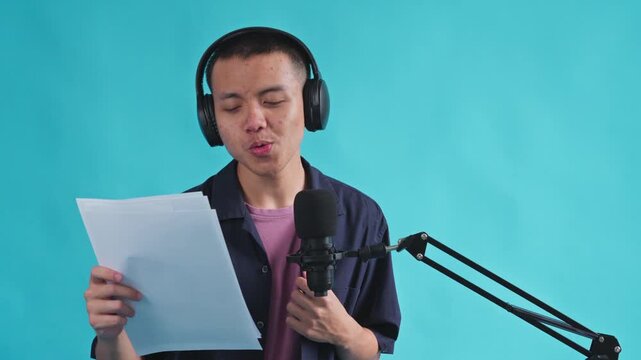 Musician singing while reading lyrics into microphone with feeling on blue backgraound
