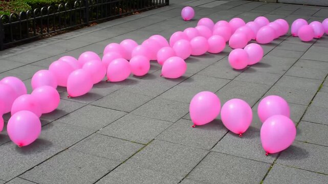 Scattered Pink Helium Balloons on Textured Pavement Creating a Playful Atmosphere for Celebrations and Events