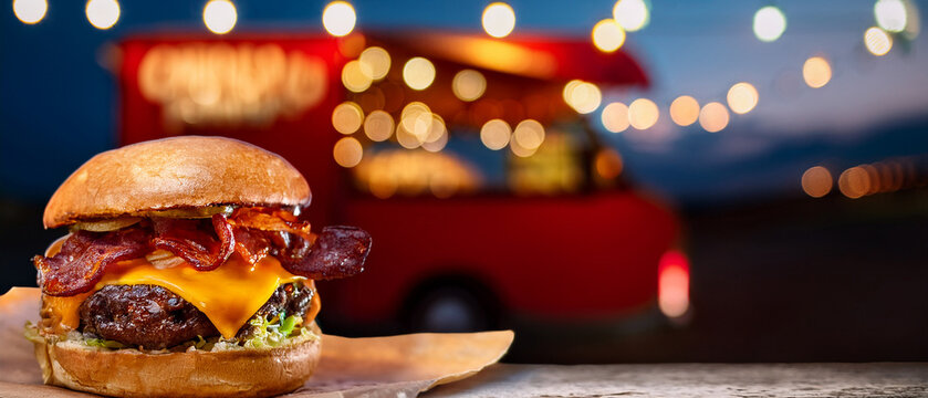 Fresh gourmet cheeseburger with bacon and blurred food truck lights background, full of copy space for ad.
