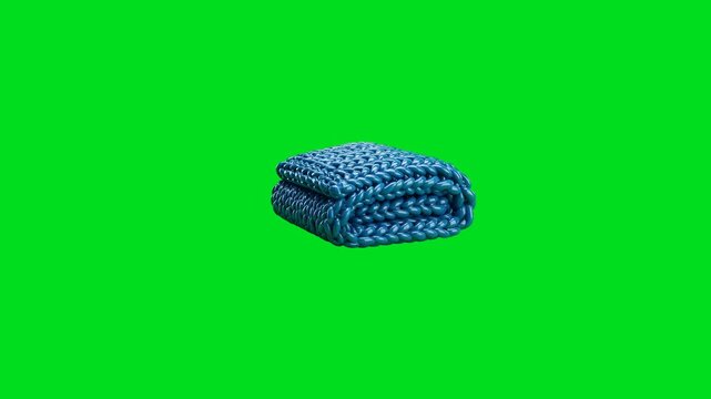 A neatly folded chunky blue knitted blanket isolated on a bright green backdrop