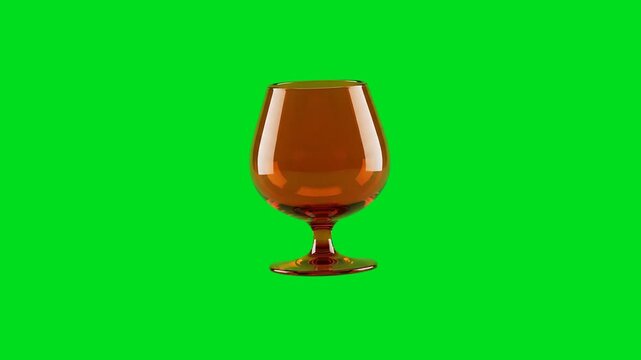 An elegant amber colored brandy snifter isolated against a vibrant green screen