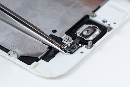 Smartphone repair close up with tweezers on internal components