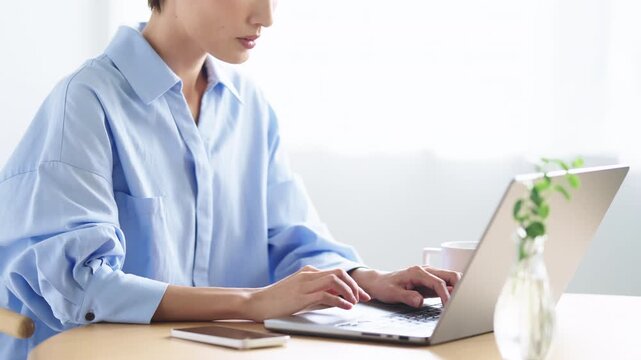 明るい室内でノートパソコンを使って作業をする日本人女性