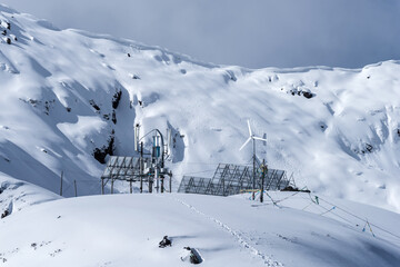 Fototapeta premium Solar panels and wind turbine on a snowy mountain pass