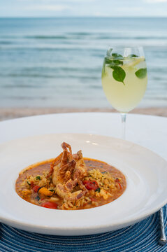 Seafood risotto with crab and a cocktail by the beach.