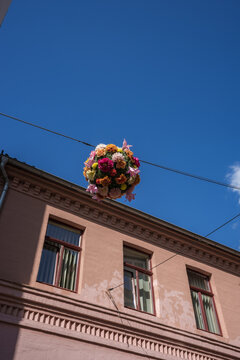 Colorful flower ball decoration hanging across a street between buildings