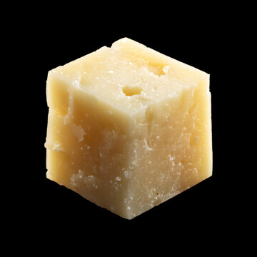 Closeup of aged cheese asiago cube isolated on black background with clipping path, concept of gourmet food and culinary quality