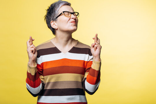 Woman closing eyes and crossing fingers on both hands, wishing for good fortune and hoping for success