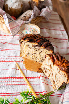 Sliced braided loaf with baked goods in background cloth
