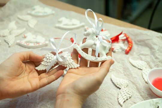 Crafting decorative white clay ornaments with angel wings and horse designs