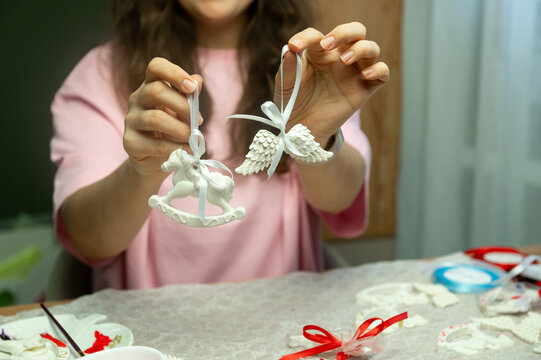 Caucasian female adult presenting handmade ceramic ornaments with horse and angel details