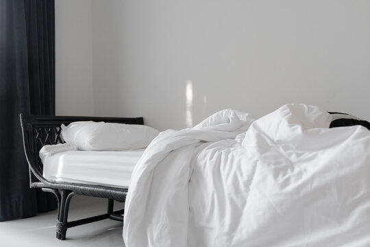 messy blanket on clean white bed and white pillow with morning light  in bedroom of house, resort or hotel, in soft focus