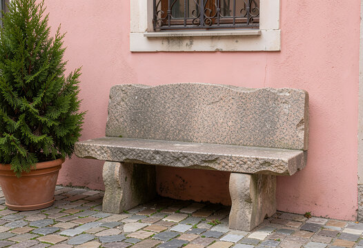 Stone bench by pink wall outdoor seating on cobblestone patio
