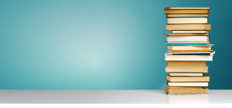 Stack of books on a white shelf against a blue wall in an e learning setup during daytime