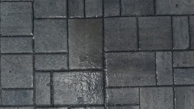 Top view of wet dark gray stone paving blocks texture background with water droplets.