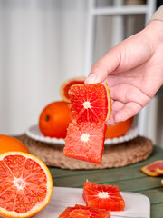 Hand Holding Fresh Blood Orange Slices with Vibrant Red Flesh in Kitchen © Nguyen