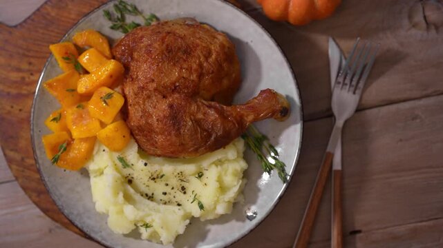 Roasted chicken quarter with glazed pumpkin, herbs and mashed potato, top view. Portion of festive autumn meal for Thanksgiving. Healthy seasonal food.