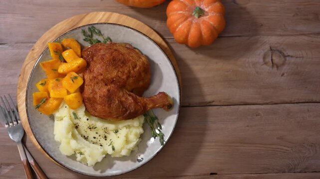 Roasted chicken quarter with glazed pumpkin, herbs and mashed potato, top view. Portion of festive autumn meal for Thanksgiving. Healthy seasonal food.
