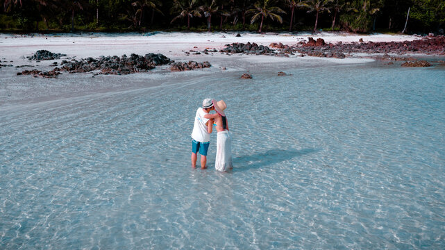 Couple tourist stay happy moment at the edge of the sea beach under shallow of the crystal clear water in summer trip on tropical island island