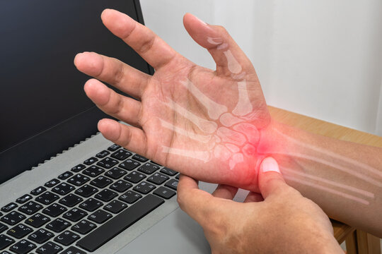 Wrist pain showing a male office worker holding his wrist due to repetitive computer work for specialized medical treatment and carpal tunnel care.