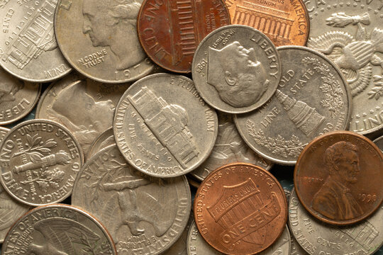 Close-up background of assorted United States coins including pennies, nickels, dimes and quarters arranged in an overlapping pile.