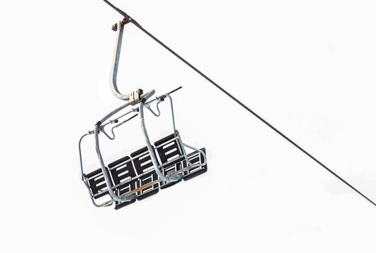 empty ski lift chair suspended on cable and isolated on white background