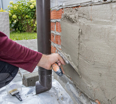 Close-up of hand using trowel to smooth mortar on brick wall