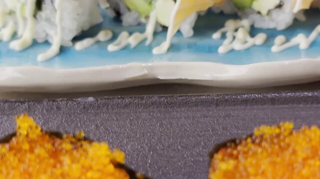 Close-up of California roll sushi arranged on a serving plate, featuring rice, seafood, avocado, and fresh ingredients with an elegant presentation.