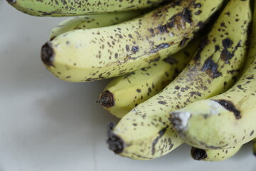 Ripe yellow bananas with brown spots on a white background © abdul.kaafii